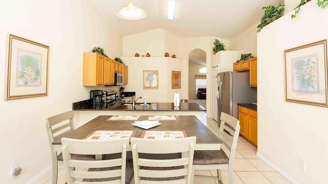 2805 Lido Key Ct, Kissimmee, FL 34747 - dining space with arched walkways, vaulted ceiling, light tile patterned floors, and baseboards