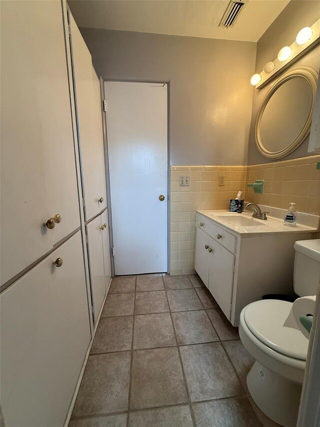 6615 Beamer Way, Orlando, FL 32807 - bathroom featuring tile walls, toilet, tile patterned flooring, vanity, and wainscoting