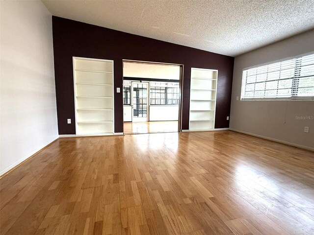 6615 Beamer Way, Orlando, FL 32807 - empty room with built in features, light wood-style flooring, a textured ceiling, and baseboards