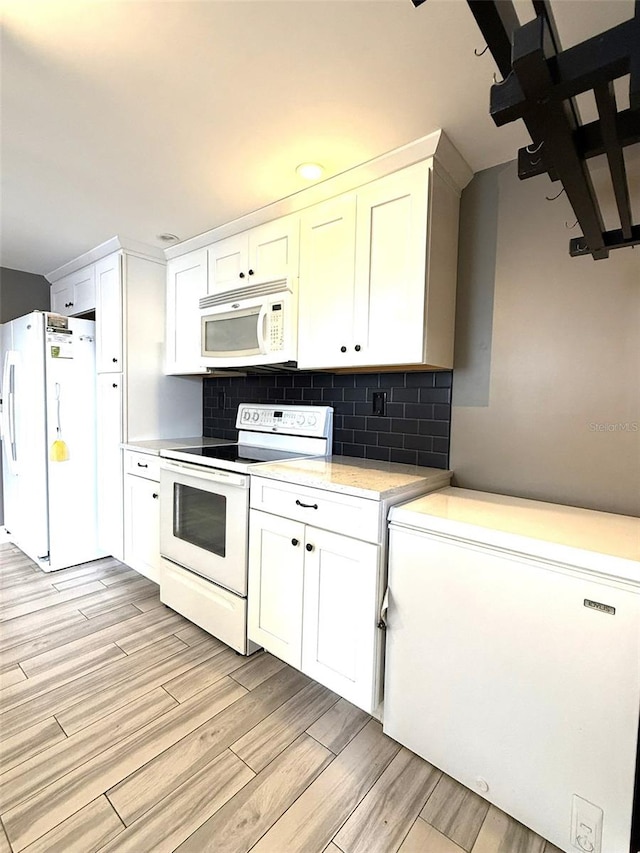 6615 Beamer Way, Orlando, FL 32807 - kitchen featuring white appliances, light countertops, light wood-style floors, backsplash, and white cabinets