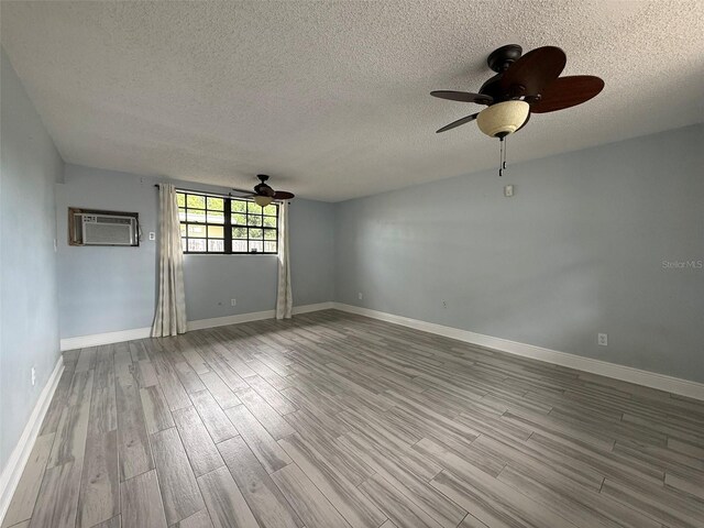 6615 Beamer Way, Orlando, FL 32807 - empty room featuring ceiling fan, wood finished floors, an AC wall unit, a textured ceiling, and baseboards