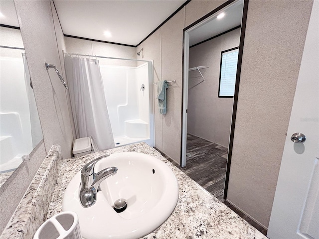 3790 NW 4th Ave, Okeechobee, FL 34972 - bathroom featuring a sink, curtained shower, a textured wall, and wood finished floors