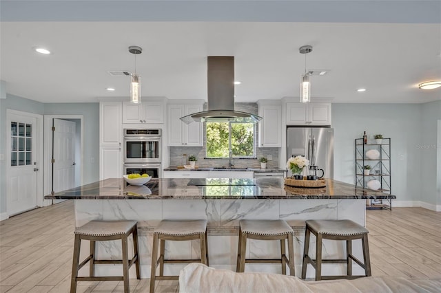 277 Sunrise Pt, Lake Mary, FL 32746 - kitchen featuring island range hood, appliances with stainless steel finishes, a kitchen bar, light wood-type flooring, and recessed lighting