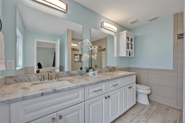 277 Sunrise Pt, Lake Mary, FL 32746 - full bath featuring toilet, a tile shower, double vanity, tile walls, and a textured ceiling