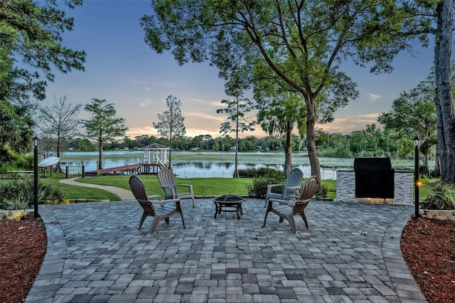 277 Sunrise Pt, Lake Mary, FL 32746 - patio terrace at dusk with an outdoor fire pit, a lawn, a water view, and area for grilling