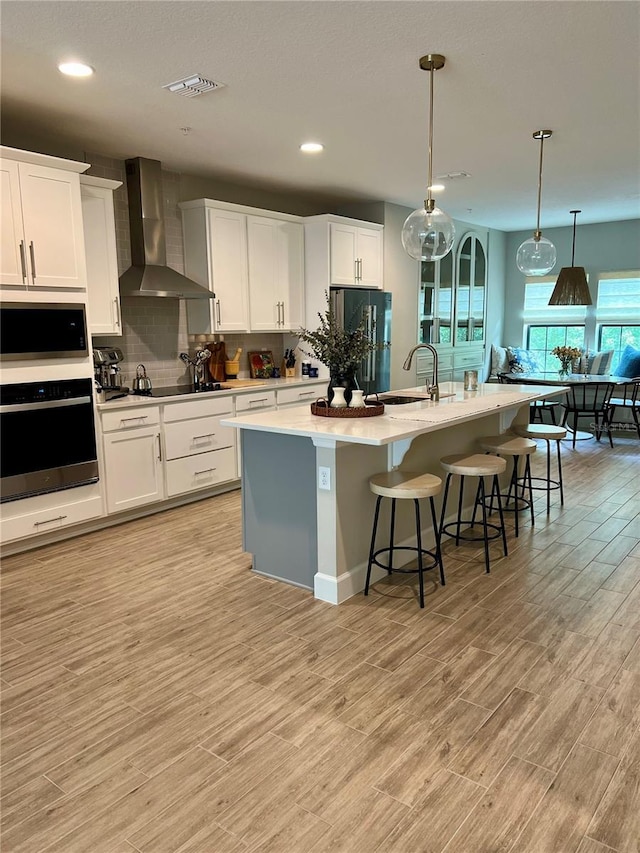 1266 Spotted Sandpiper Loop, Winter Springs, FL 32708 - kitchen featuring stainless steel appliances, wall chimney exhaust hood, a sink, light wood-type flooring, and backsplash