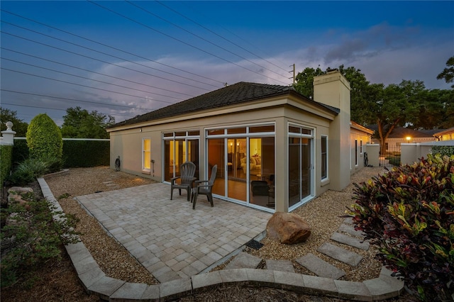 5973 Chesapeake Park Unit 58, Orlando, FL 32819 - back of property at dusk with stucco siding, a patio area, a chimney, and a fenced backyard