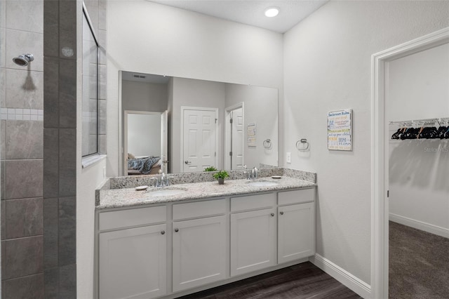 4811 SW 108th Place Rd, Ocala, FL 34476 - ensuite bathroom featuring tiled shower, double vanity, baseboards, a walk in closet, and wood finished floors