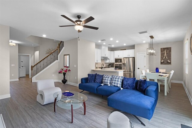 7745 Somersworth Dr, Kissimmee, FL 34747 - living room with baseboards, light wood-style floors, ceiling fan, recessed lighting, and stairway