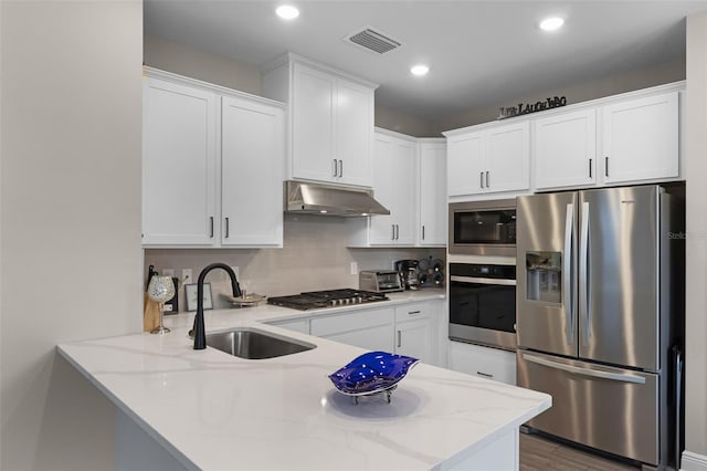 7745 Somersworth Dr, Kissimmee, FL 34747 - kitchen with stainless steel appliances, a sink, under cabinet range hood, a peninsula, and light stone counters