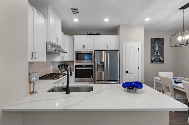 7745 Somersworth Dr, Kissimmee, FL 34747 - kitchen with stainless steel appliances, under cabinet range hood, a sink, white cabinetry, and recessed lighting