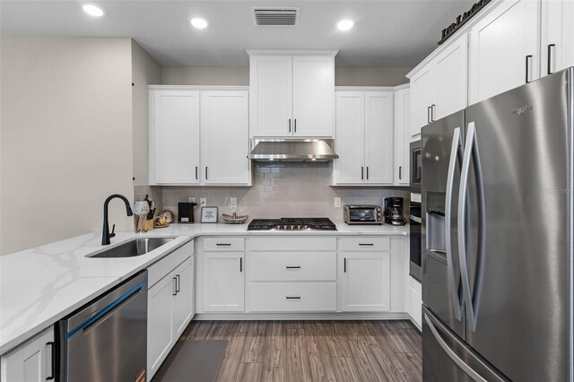 7745 Somersworth Dr, Kissimmee, FL 34747 - kitchen with appliances with stainless steel finishes, under cabinet range hood, a sink, white cabinetry, and backsplash