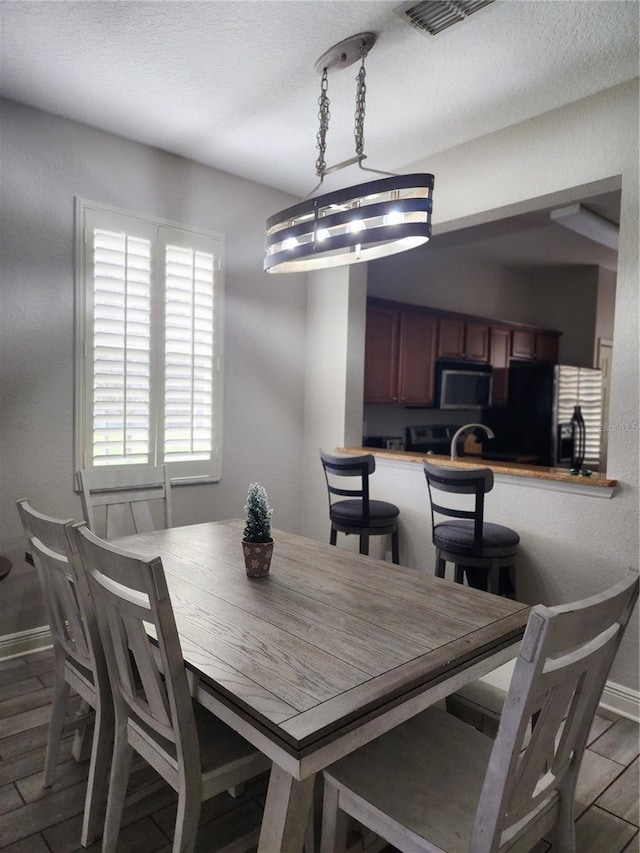 3500 Calabria Ave, Davenport, FL 33897 - dining space with baseboards, light wood-style flooring, and a textured ceiling