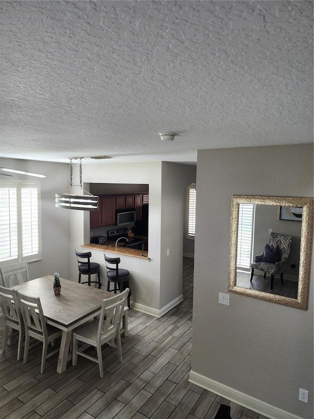 3500 Calabria Ave, Davenport, FL 33897 - dining room featuring baseboards, wood finished floors, plenty of natural light, and a textured ceiling