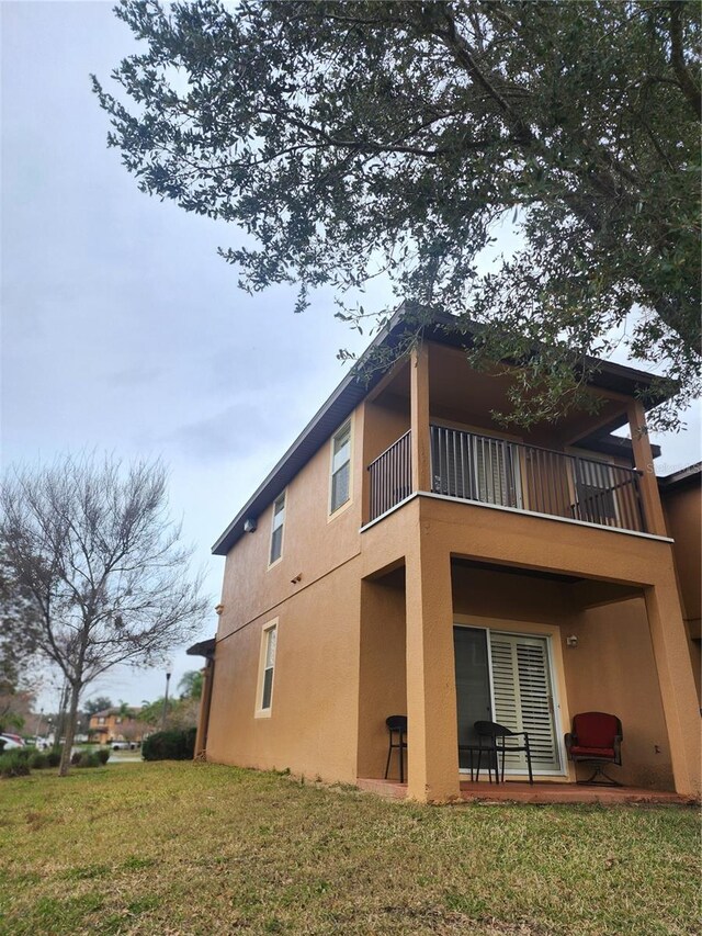 3500 Calabria Ave, Davenport, FL 33897 - rear view of house featuring a balcony, stucco siding, and a lawn