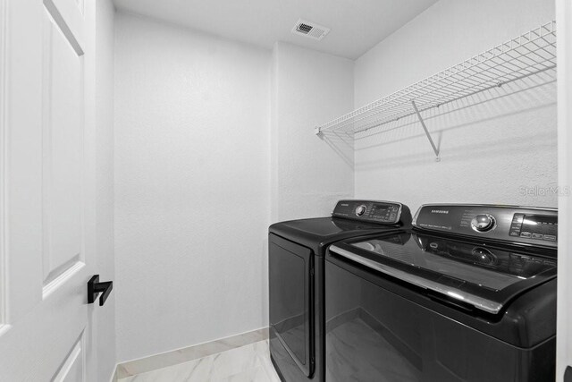 laundry room with washing machine and clothes dryer, baseboards, and light marble finish flooring