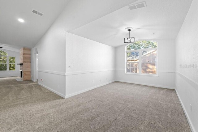 carpeted empty room featuring vaulted ceiling and baseboards