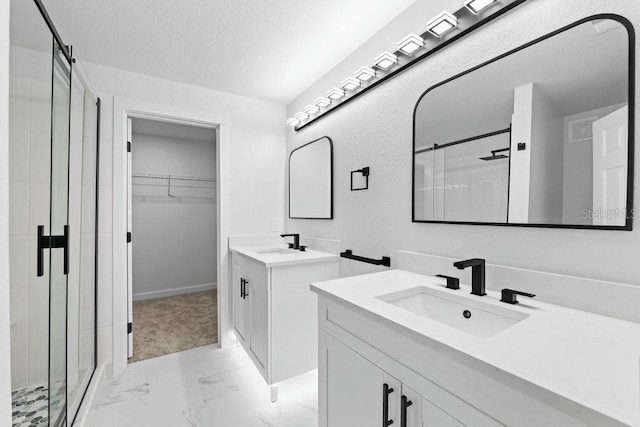 bathroom with marble look tiles, a shower stall, two vanities, a spacious closet, and a textured ceiling