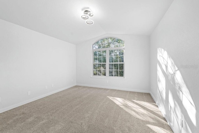 unfurnished room featuring lofted ceiling, carpet, and baseboards