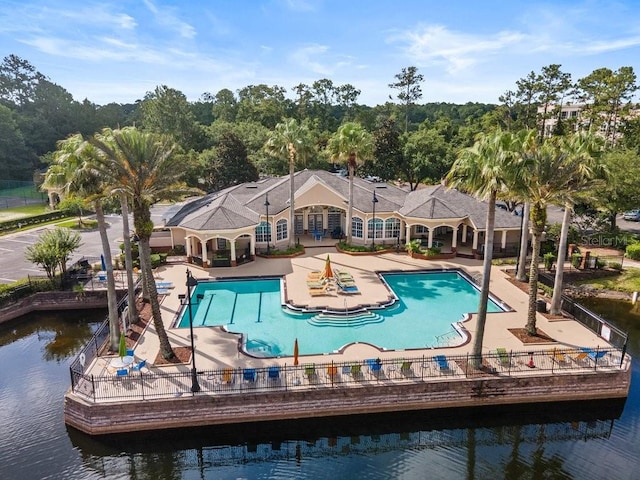 community pool with a patio, a water view, and fence