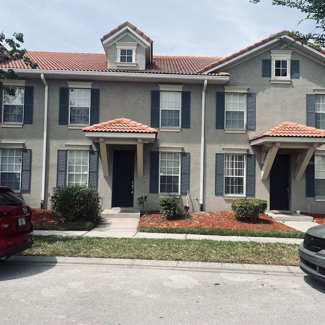 view of property with stucco siding and a tile roof