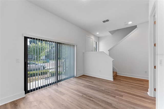 unfurnished living room featuring plenty of natural light, wood finished floors, stairway, and recessed lighting