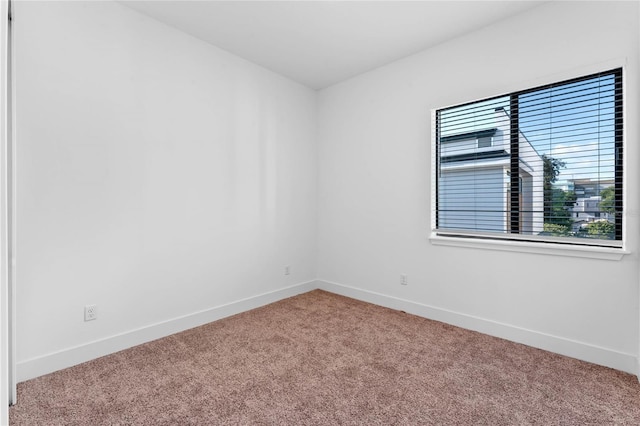 carpeted empty room featuring baseboards