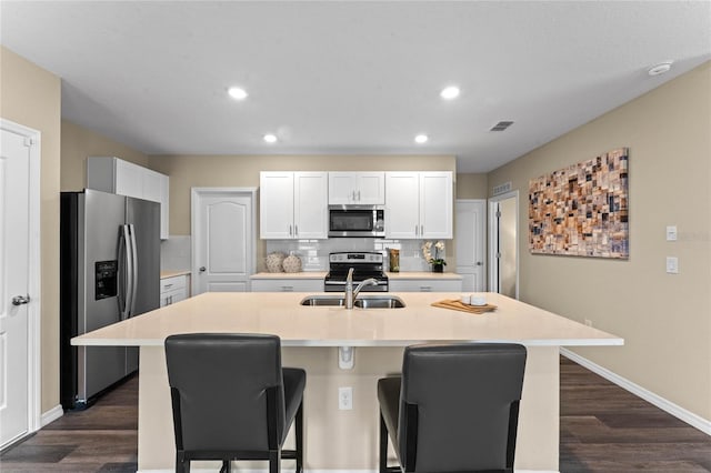kitchen with appliances with stainless steel finishes, a sink, a breakfast bar, dark wood finished floors, and recessed lighting