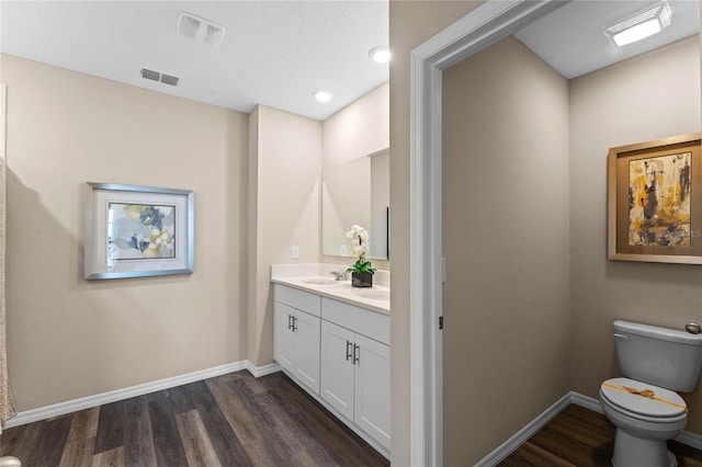 bathroom featuring wood finished floors, toilet, baseboards, and double vanity