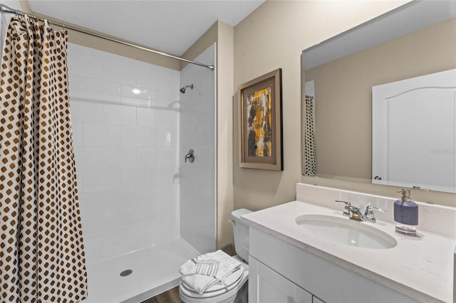 bathroom featuring toilet, a tile shower, and vanity