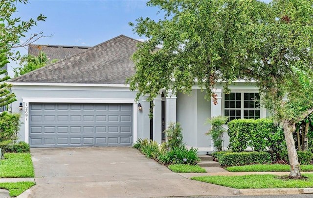 view of front facade featuring roof with shingles, stucco siding, driveway, and a garage