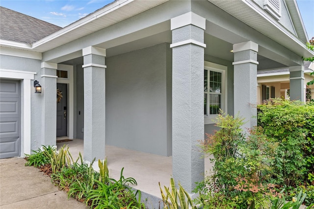 property entrance with roof with shingles, a porch, and stucco siding