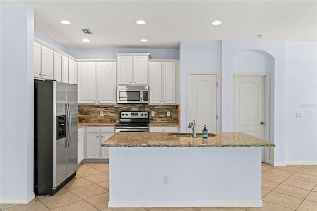 kitchen with stainless steel appliances, a sink, light tile patterned floors, light stone counters, and recessed lighting