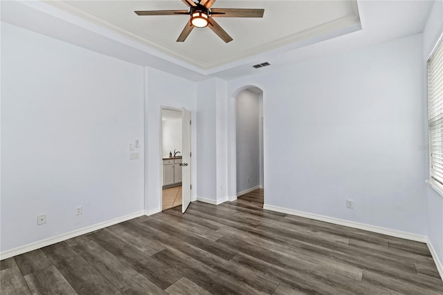unfurnished room featuring arched walkways, ceiling fan, dark wood-type flooring, baseboards, and crown molding
