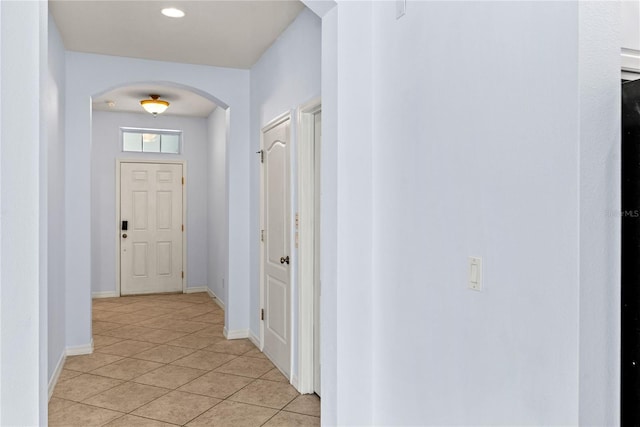 hall with arched walkways, light tile patterned floors, and baseboards