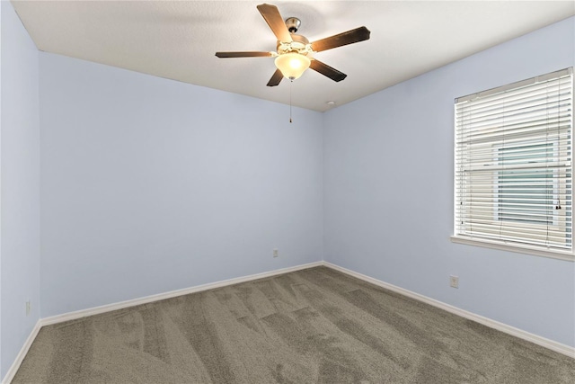 carpeted empty room featuring ceiling fan and baseboards