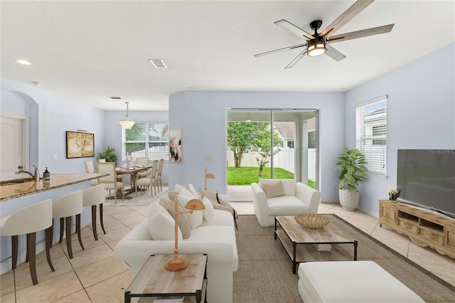 living room with light tile patterned floors, plenty of natural light, ceiling fan, and arched walkways