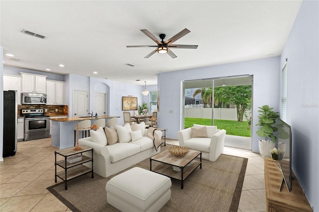 living area featuring light tile patterned flooring, arched walkways, a ceiling fan, and recessed lighting