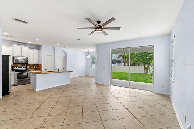 kitchen featuring appliances with stainless steel finishes, a sink, backsplash, ceiling fan, and light tile patterned flooring