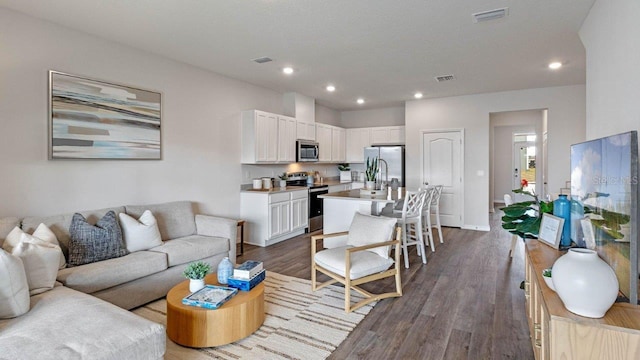 living area with dark wood-type flooring and recessed lighting