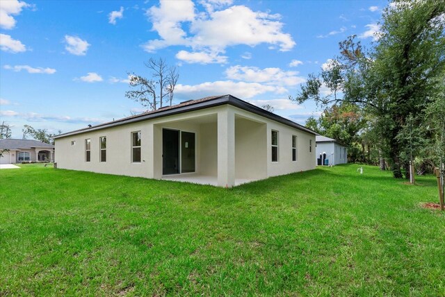 2919 Cascabel Ter, North Port, FL 34286 - back of house featuring stucco siding, a lawn, and a patio