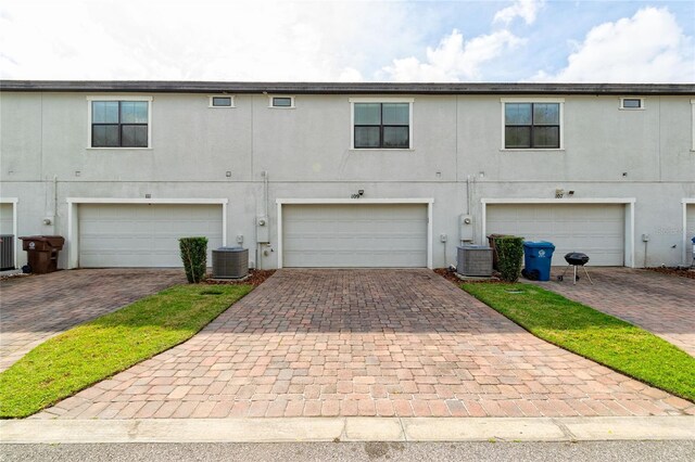 109 Kenny Blvd, Haines City, FL 33844 - rear view of house featuring stucco siding, central AC, driveway, and a garage
