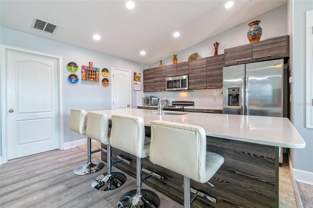 109 Kenny Blvd, Haines City, FL 33844 - kitchen featuring appliances with stainless steel finishes, a kitchen breakfast bar, light countertops, modern cabinets, and an island with sink