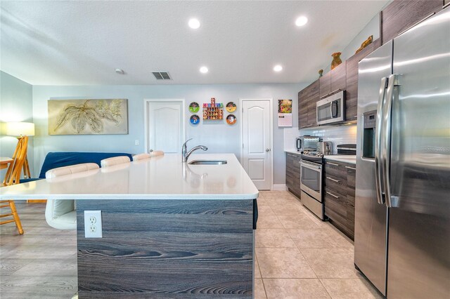 109 Kenny Blvd, Haines City, FL 33844 - kitchen featuring appliances with stainless steel finishes, a sink, modern cabinets, light countertops, and a center island with sink