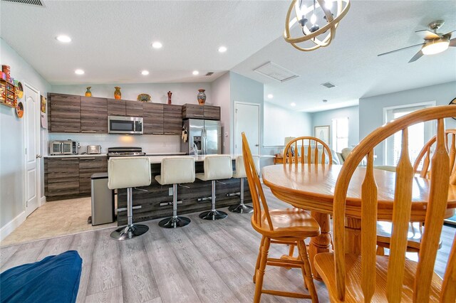 109 Kenny Blvd, Haines City, FL 33844 - kitchen featuring stainless steel appliances, light wood finished floors, a center island with sink, light countertops, and a textured ceiling