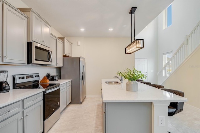 1221 Aloha Blvd, Davenport, FL 33897 - kitchen with appliances with stainless steel finishes, a sink, a breakfast bar area, gray cabinets, and a kitchen island with sink