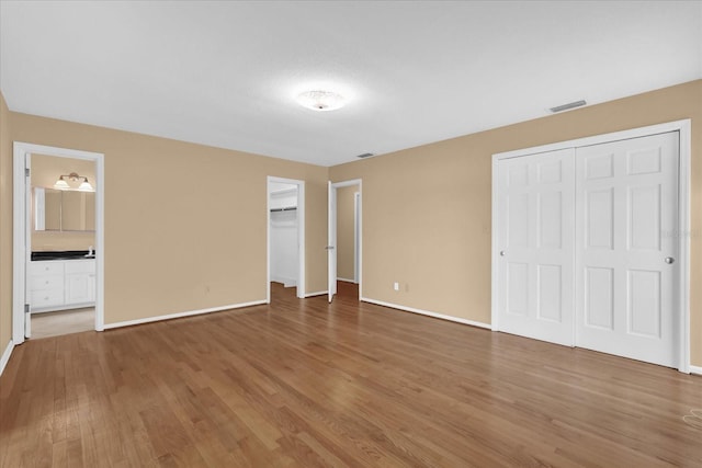 633 Balmoral Rd, Winter Park, FL 32789 - unfurnished bedroom featuring wood finished floors, baseboards, and connected bathroom