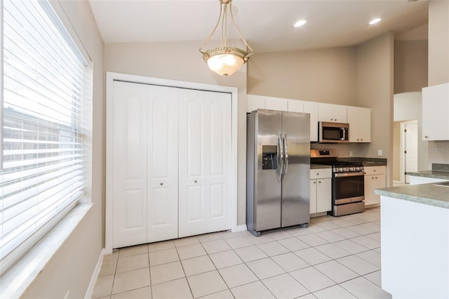 24237 Rolling View Ct, Lutz, FL 33559 - kitchen featuring stainless steel appliances, white cabinets, light tile patterned flooring, baseboards, and high vaulted ceiling