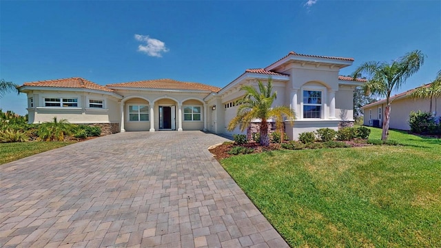 8851 Fallen Oak Dr, Davenport, FL 33896 - mediterranean / spanish house featuring decorative driveway, stucco siding, a front yard, a tiled roof, and an attached garage