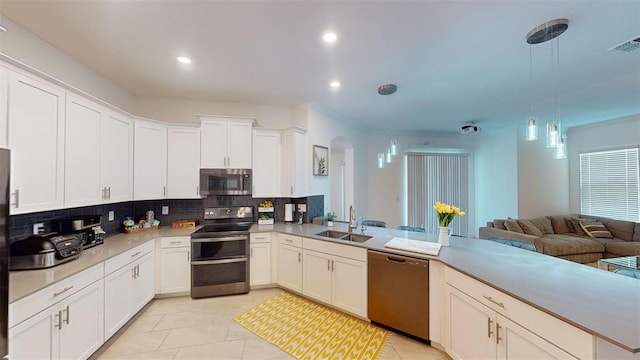 8851 Fallen Oak Dr, Davenport, FL 33896 - kitchen featuring appliances with stainless steel finishes, a sink, backsplash, arched walkways, and light countertops
